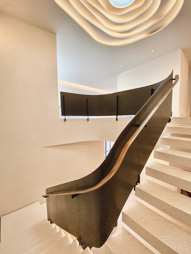 Escalier ruban avec rampe intérieure en acier et main courante en laiton