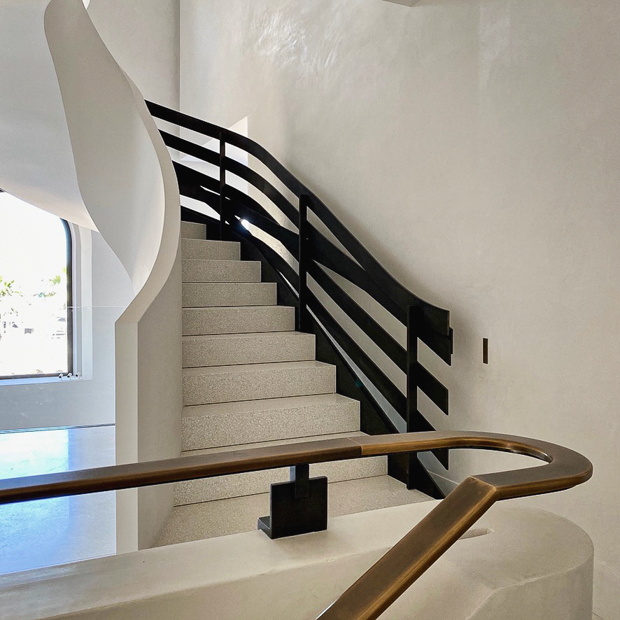 Escalier terrazzo : courbes élégantes, rampe métallique, main courante en laiton et habillage staff